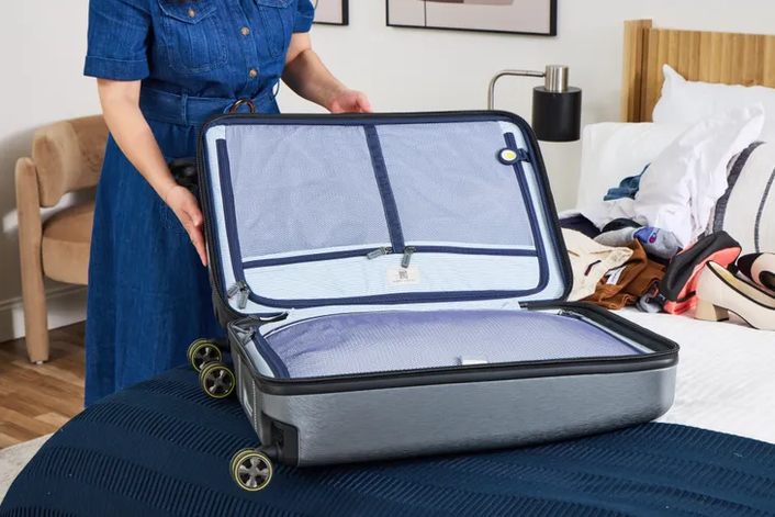 close-up of a trunk-style suitcase's front zipper compartment opened flat, laptop sleeve visible